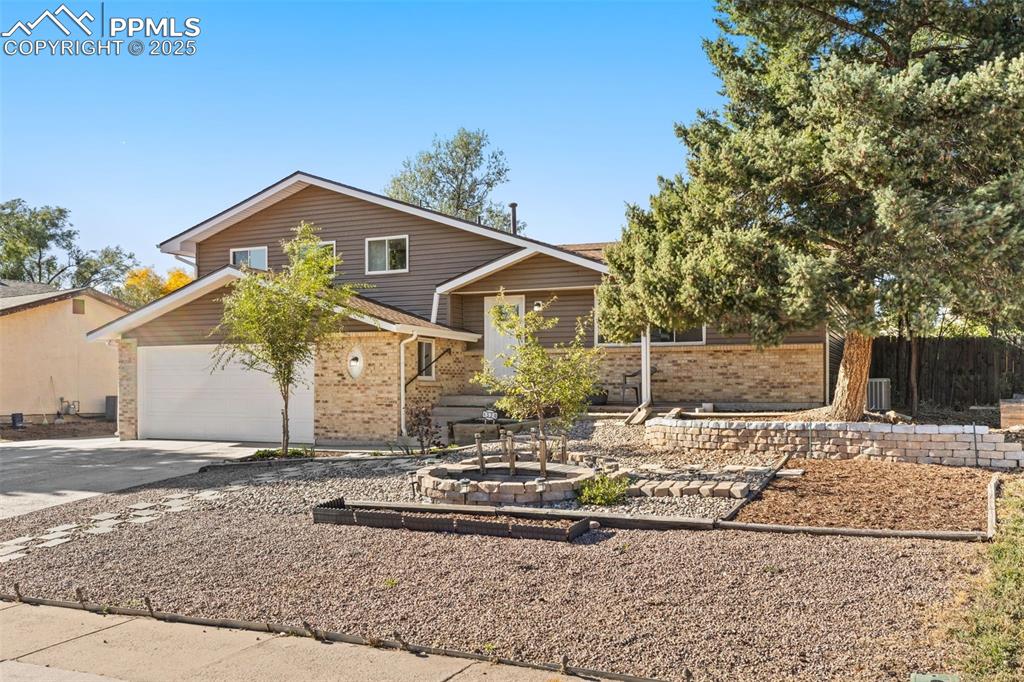 Image 9 of 44: View of front facade with brick siding, concrete driveway, and a garage