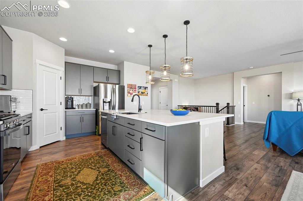 Image 10 of 49: Kitchen with gray cabinetry, dark wood finished floors, stainless steel app