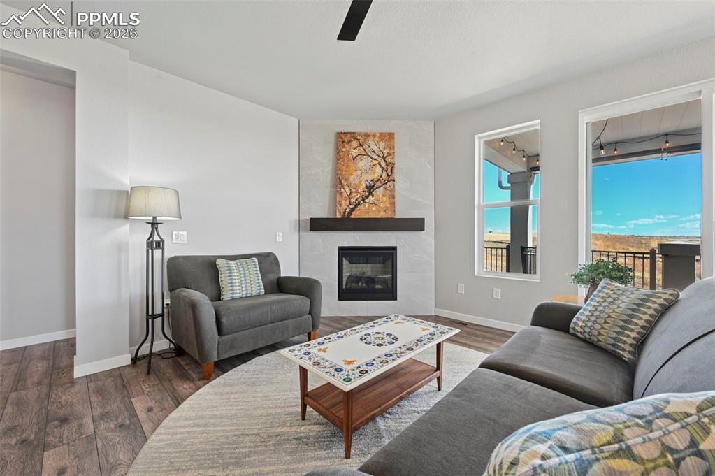 Image 14 of 49: Living room featuring wood finished floors, a fireplace, and a ceiling fan