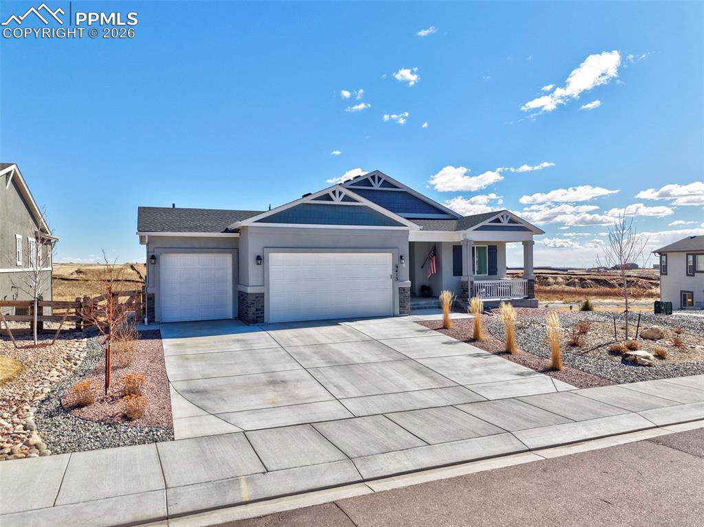 Image 2 of 49: View of front of home featuring an attached garage, driveway, stone siding,