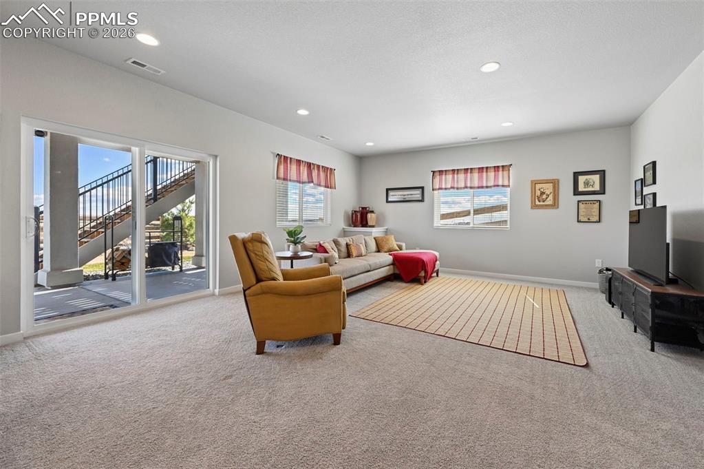 Image 29 of 49: Basement family room with light colored carpet and recessed lighting