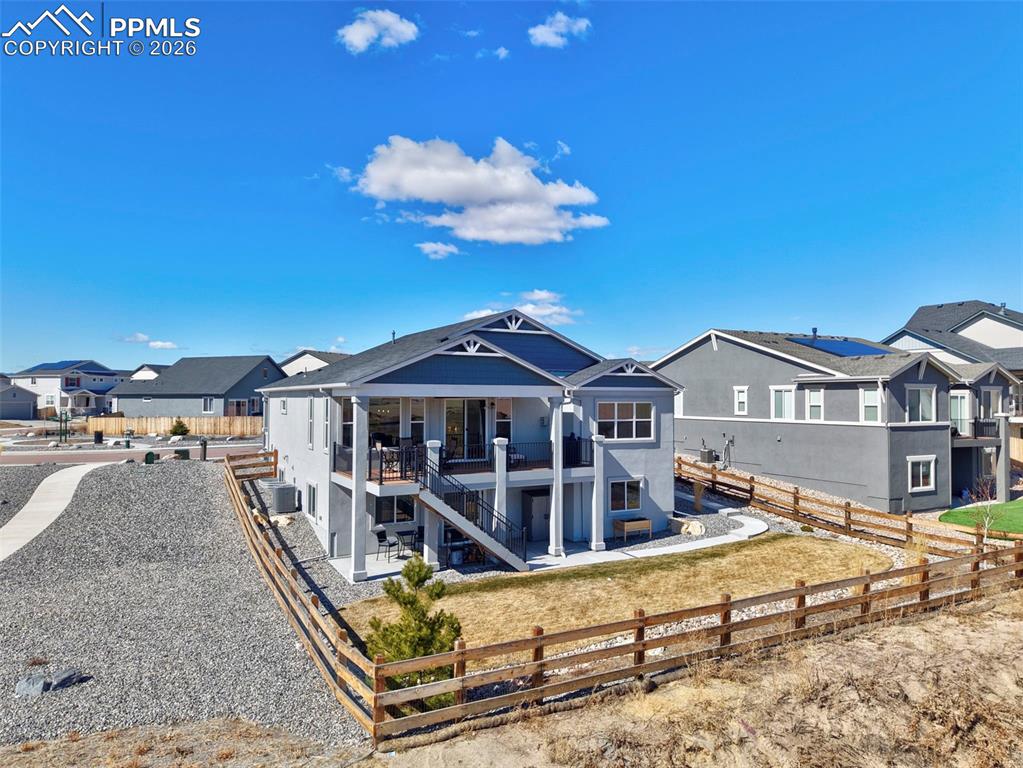 Image 45 of 49: Back of house featuring a fenced backyard, a residential view, and a patio 