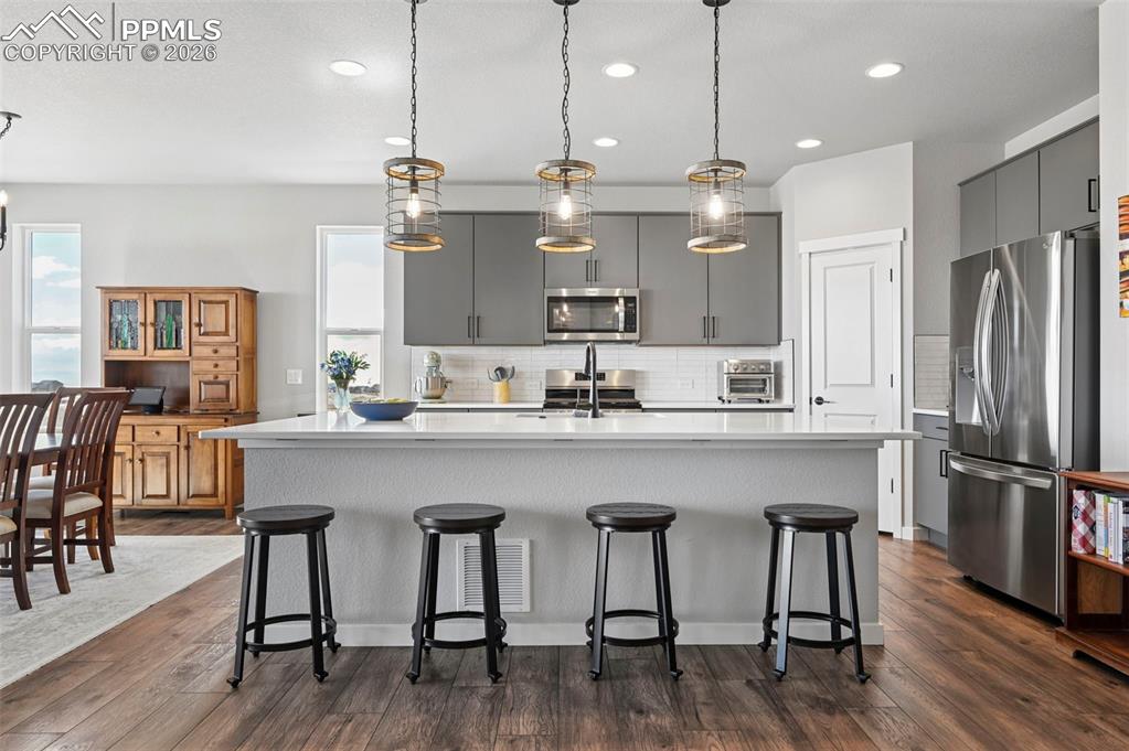 Image 8 of 49: Kitchen with a center island with sink, stainless steel appliances, gray ca