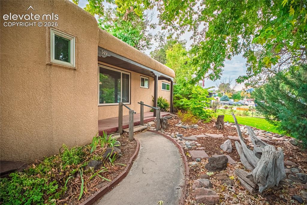 Image 2 of 44: Stucco exterior with a covered entry, sliding glass door, and a curved conc