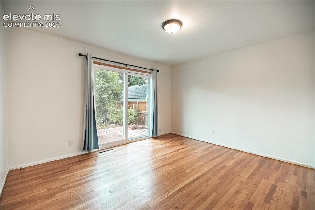 Image 21 of 44: Hardwood flooring, sliding glass door, overhead lighting fixture, white wal