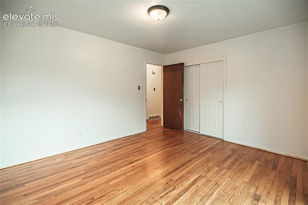 Image 23 of 44: Hardwood flooring, white painted walls, ceiling-mounted light fixture, wood