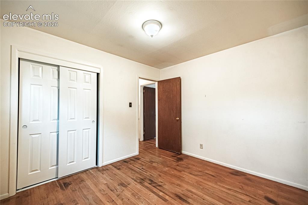 Image 27 of 44: Wood-finish flooring, white walls, and a ceiling-mounted light fixture