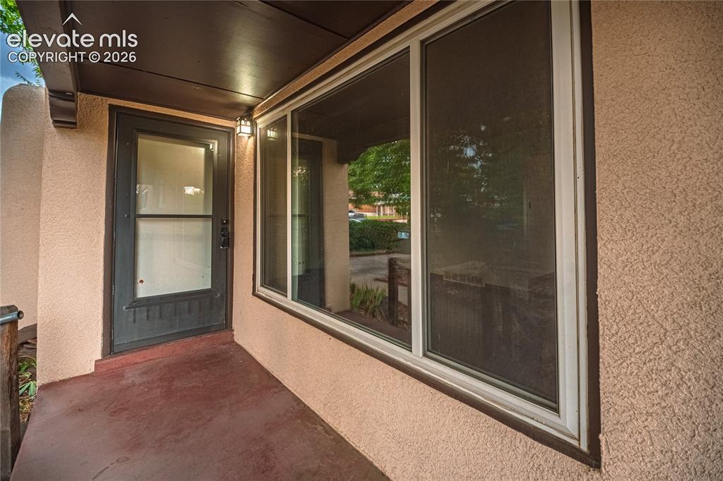Image 3 of 44: Stucco exterior with a large picture window, dark wood-finish soffit, exter