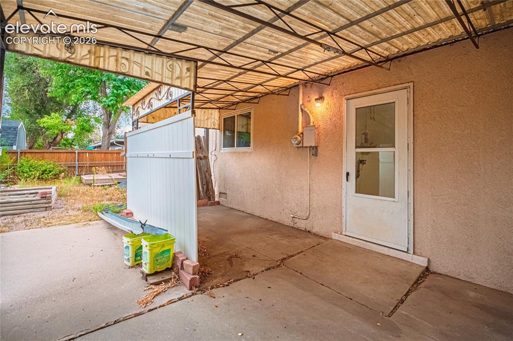 Image 30 of 44: Covered patio with a concrete surface, exterior door, and stucco siding