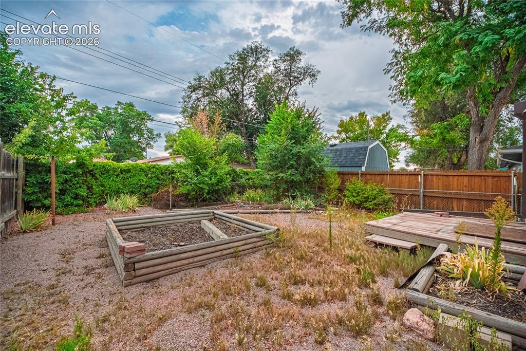 Image 32 of 44: Expansive outdoor space featuring a wood fence, raised garden beds, and a w