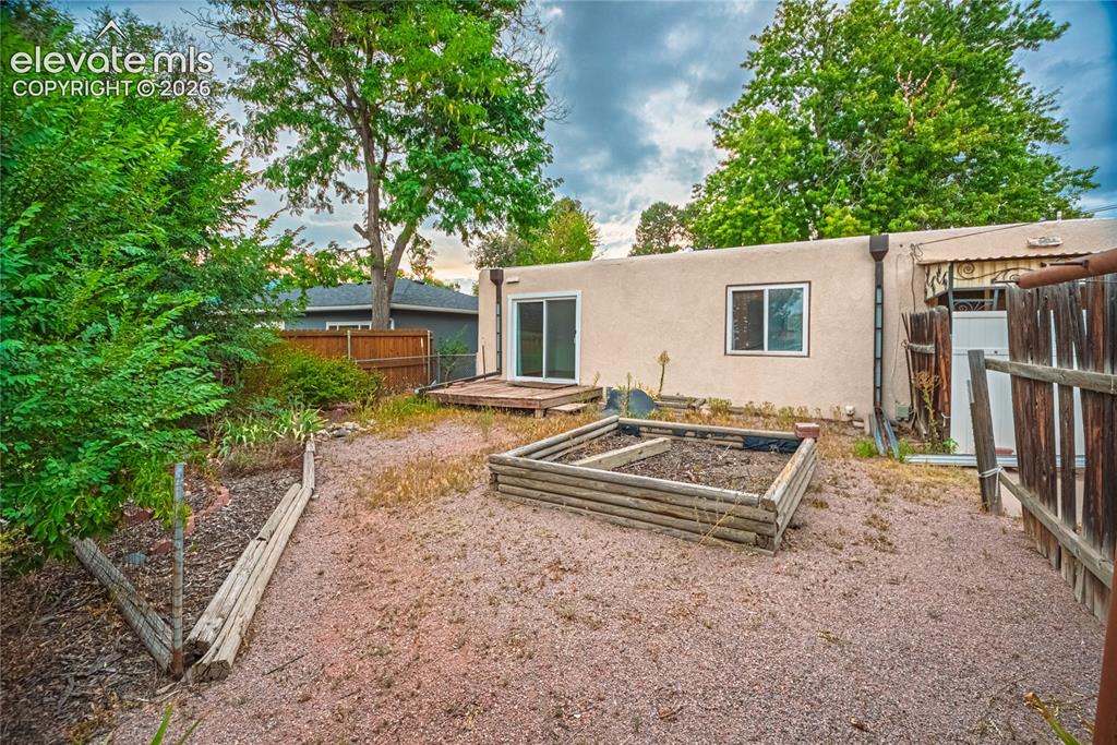 Image 35 of 44: Rear exterior with stucco finish, sliding glass door, and a raised garden b
