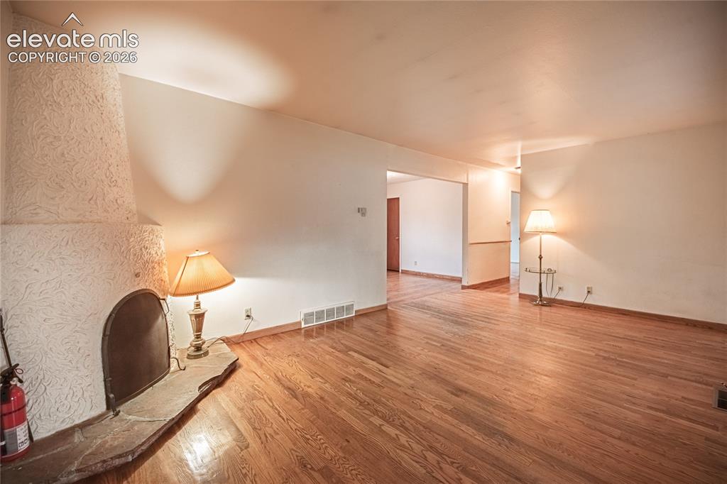 Image 4 of 44: Hardwood flooring throughout, textured fireplace with stone hearth, and whi