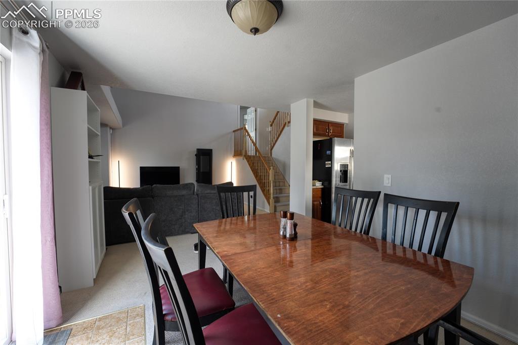 Image 12 of 45: Dining area featuring a wood-finish table, dark-toned chairs, and an overhe