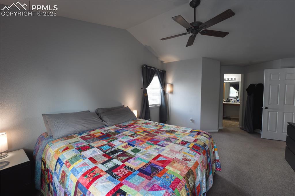 Image 19 of 45: Vaulted ceiling bedroom with a ceiling fan, carpeted flooring, and window t