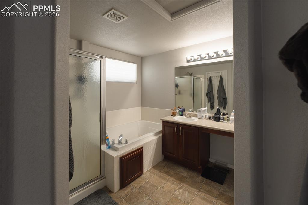 Image 20 of 45: Full bathroom featuring a built-in tub, separate glass-enclosed shower, dua