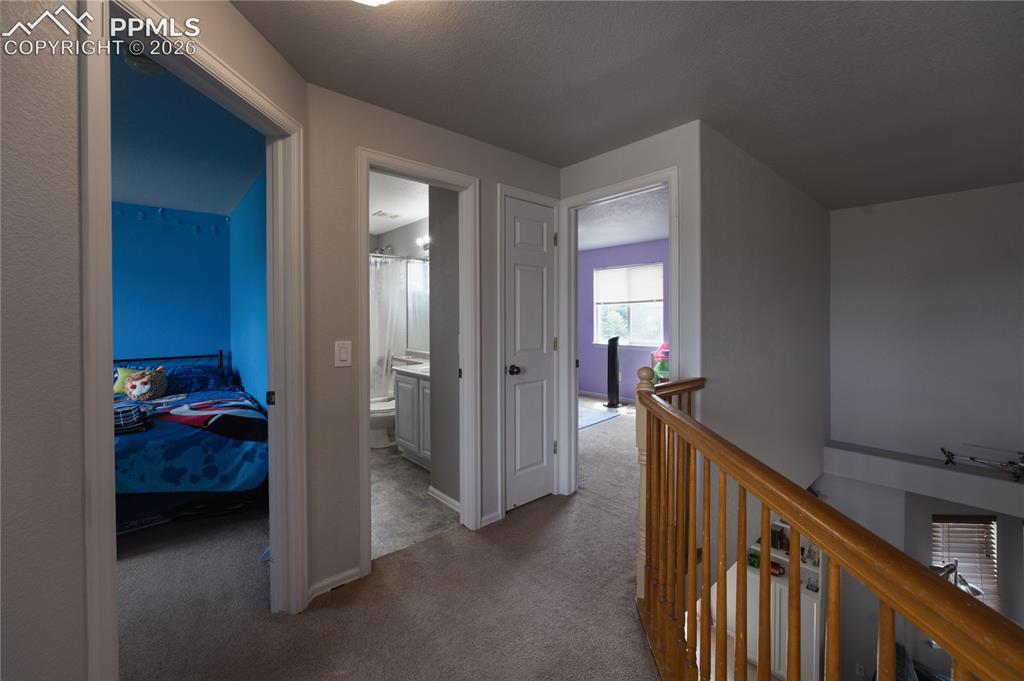 Image 22 of 45: Upper-level hallway featuring neutral wall paint and carpeted flooring