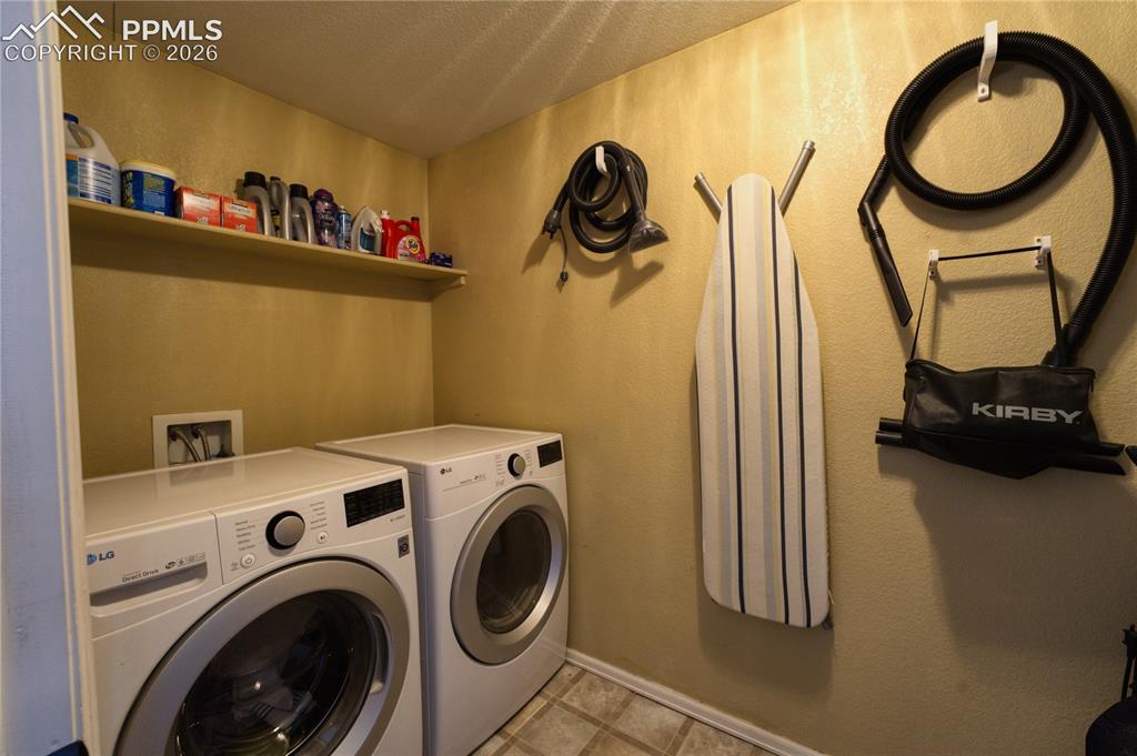 Image 29 of 45: Dedicated laundry area featuring a wall-mounted shelf, light-toned wall pai
