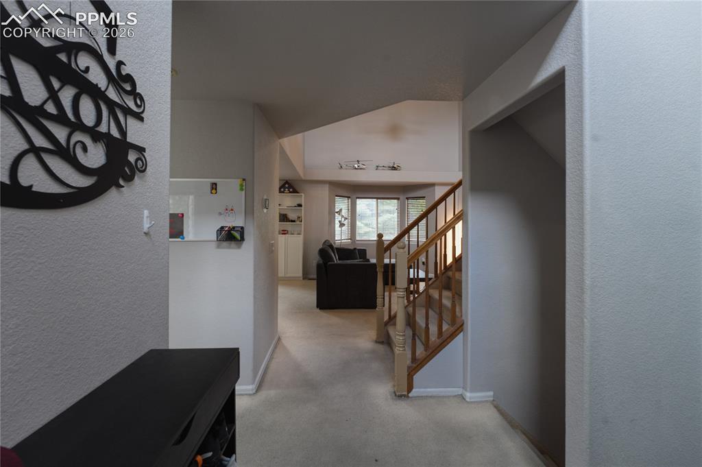 Image 3 of 45: Carpeted entryway with a staircase featuring wood newel posts and banisters