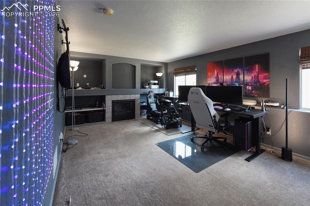 Image 36 of 45: Carpeted room featuring a fireplace with a tiled surround, built-in shelvin