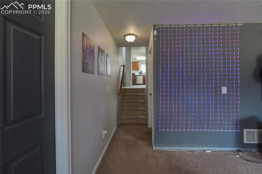 Image 38 of 45: Carpeted hallway with a staircase featuring wood banister and treads