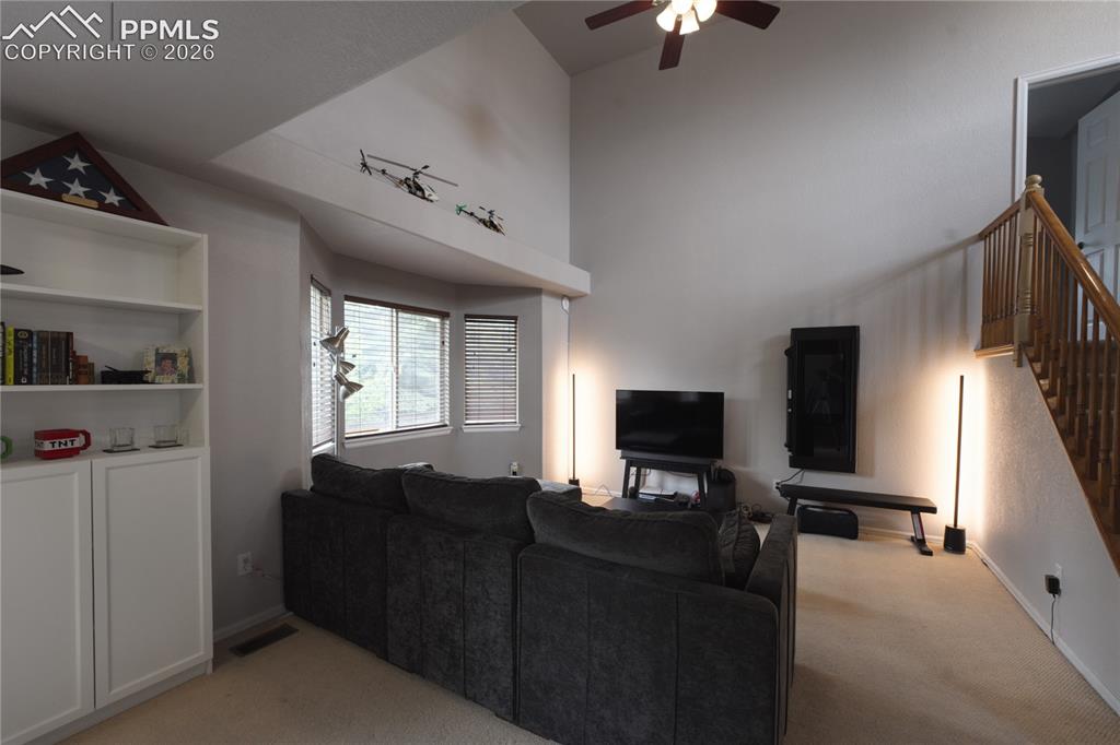Image 4 of 45: Living area featuring vaulted ceilings, a ceiling fan, bay windows with bli