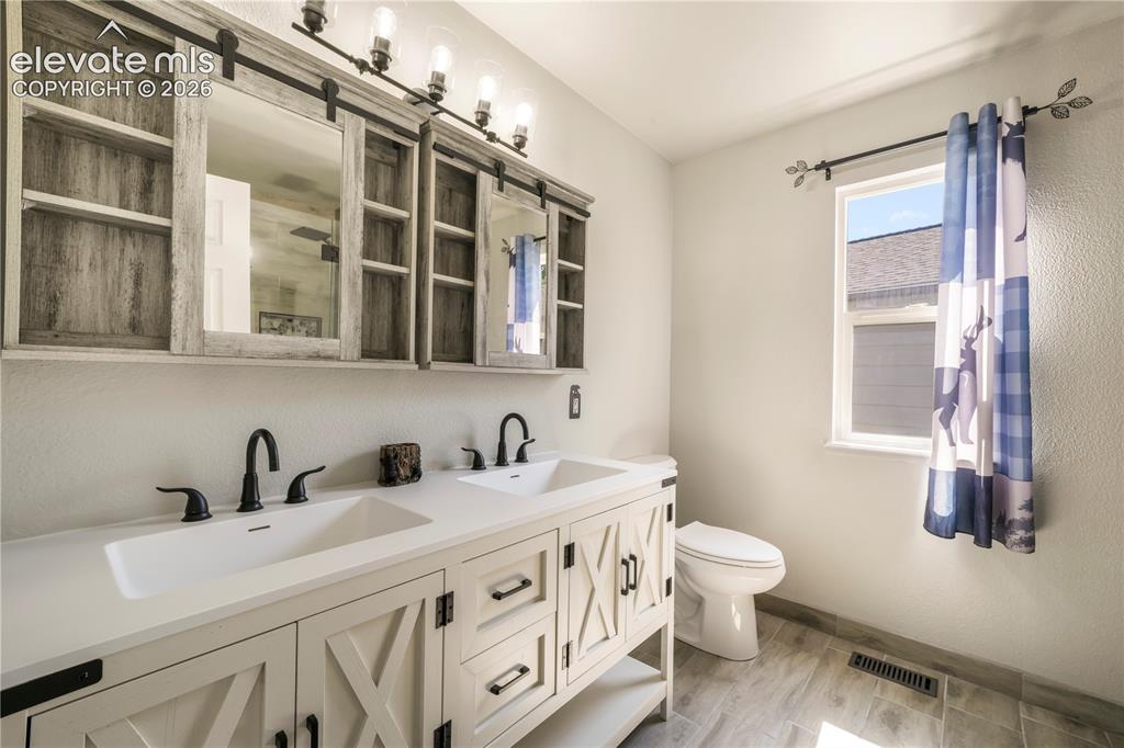 Image 28 of 50: Upstairs primary updated bathroom with large walk in shower and dual vantie