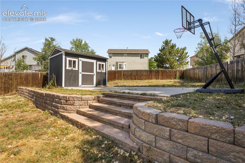 Image 47 of 50: Back of home with large backyard patio, multiple levels, basketball goal an