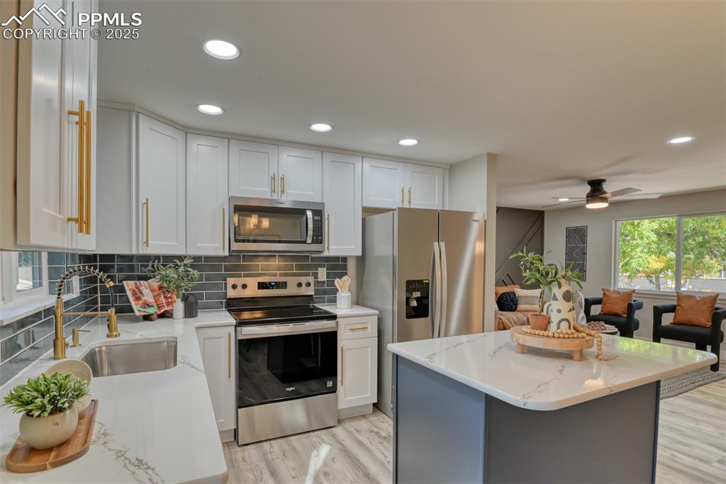 Image 10 of 48: Kitchen with stainless steel appliances, white cabinetry, decorative backsp