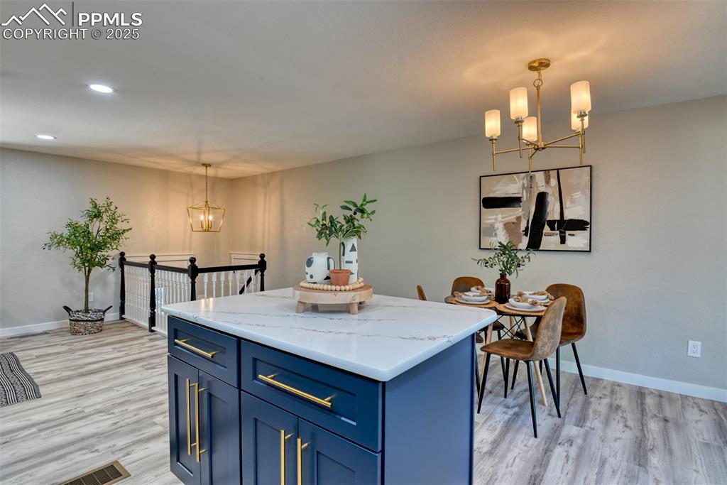 Image 11 of 48: Kitchen with a chandelier, blue cabinets, decorative light fixtures, and re