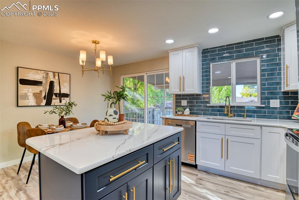 Image 13 of 48: Kitchen featuring tasteful backsplash, white cabinetry, light stone counter