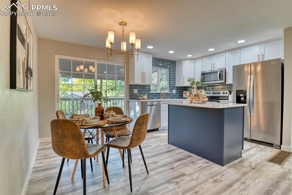Image 15 of 48: Kitchen with stainless steel appliances, white cabinetry, decorative backsp