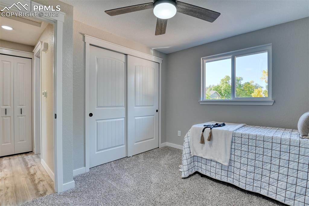 Image 24 of 48: Bedroom with light colored carpet, a closet, and a ceiling fan