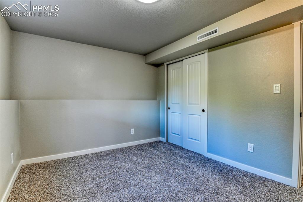 Image 32 of 48: Unfurnished bedroom with carpet, a closet, and a textured ceiling