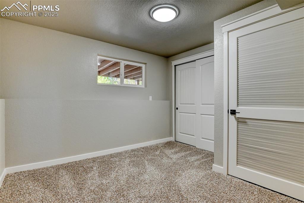 Image 38 of 48: Unfurnished bedroom with carpet floors, a textured ceiling, and a closet