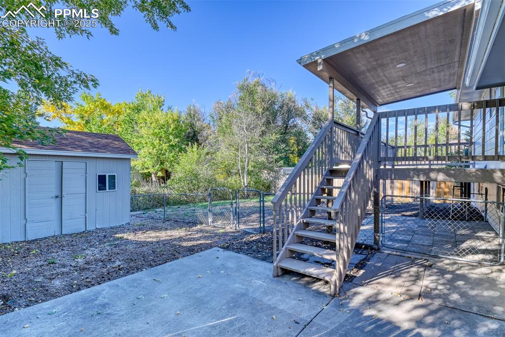Image 42 of 48: Fenced backyard with a gate, a patio, a storage unit, and stairway