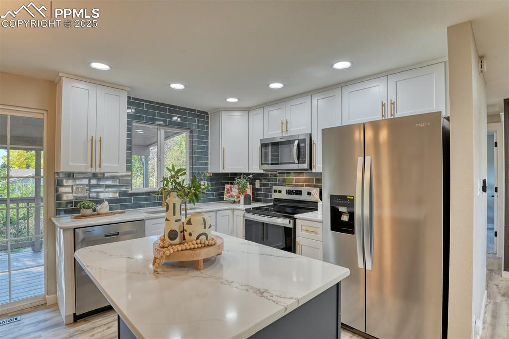 Image 9 of 48: Kitchen featuring stainless steel appliances, decorative backsplash, light 