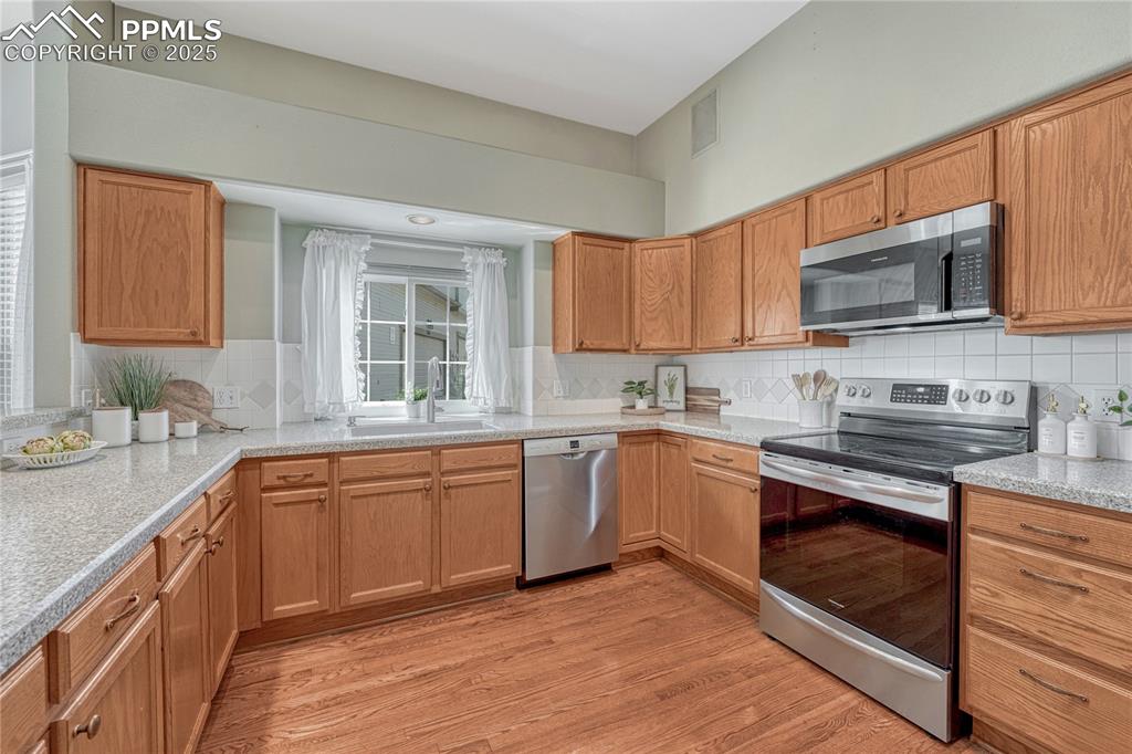 Image 4 of 47: Spacious kitchen with hardwood flooring and window over the kitchen sink