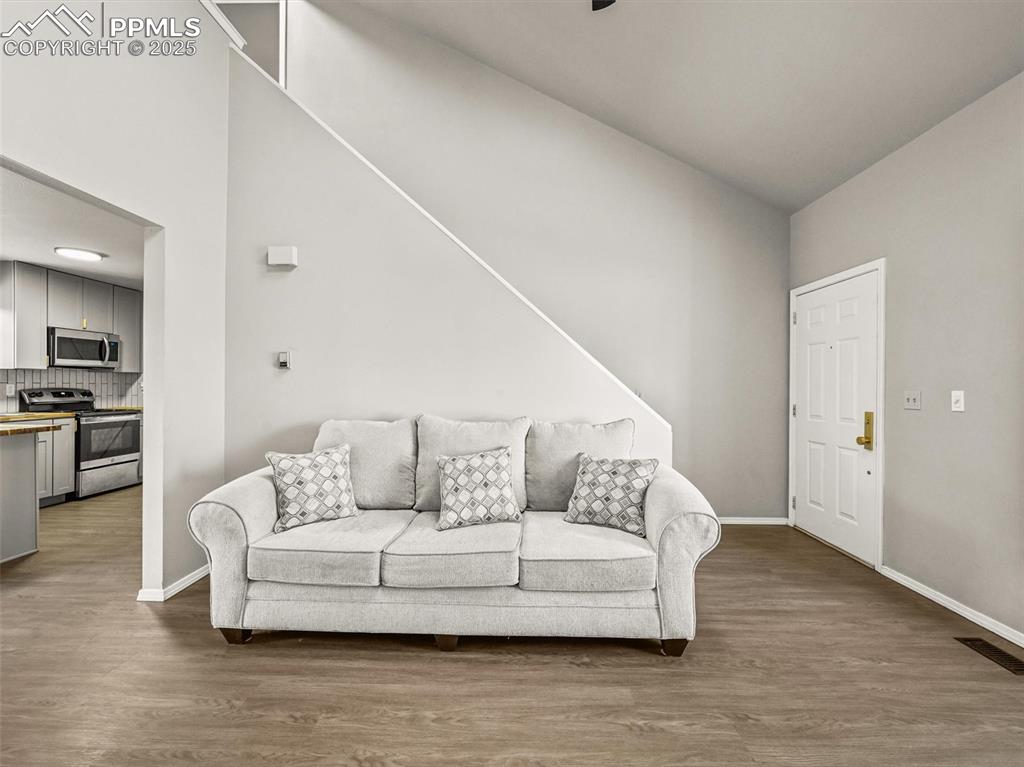 Image 10 of 47: Living room featuring wood finished floors, baseboards, and vaulted ceiling