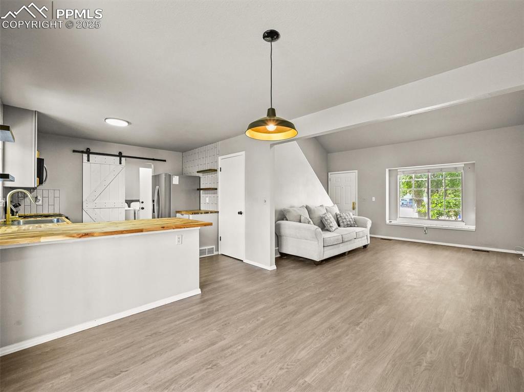 Image 12 of 47: Kitchen featuring a barn door, butcher block counters, dark wood-style floo