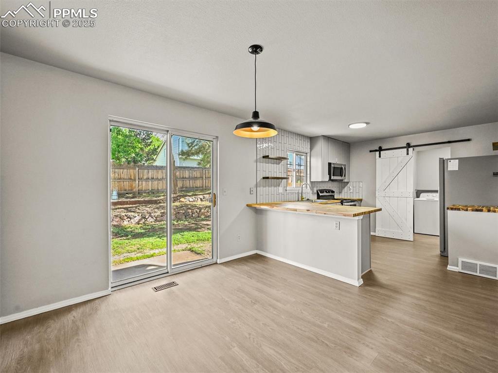 Image 13 of 47: Kitchen featuring stainless steel appliances, a barn door, washer / dryer,
