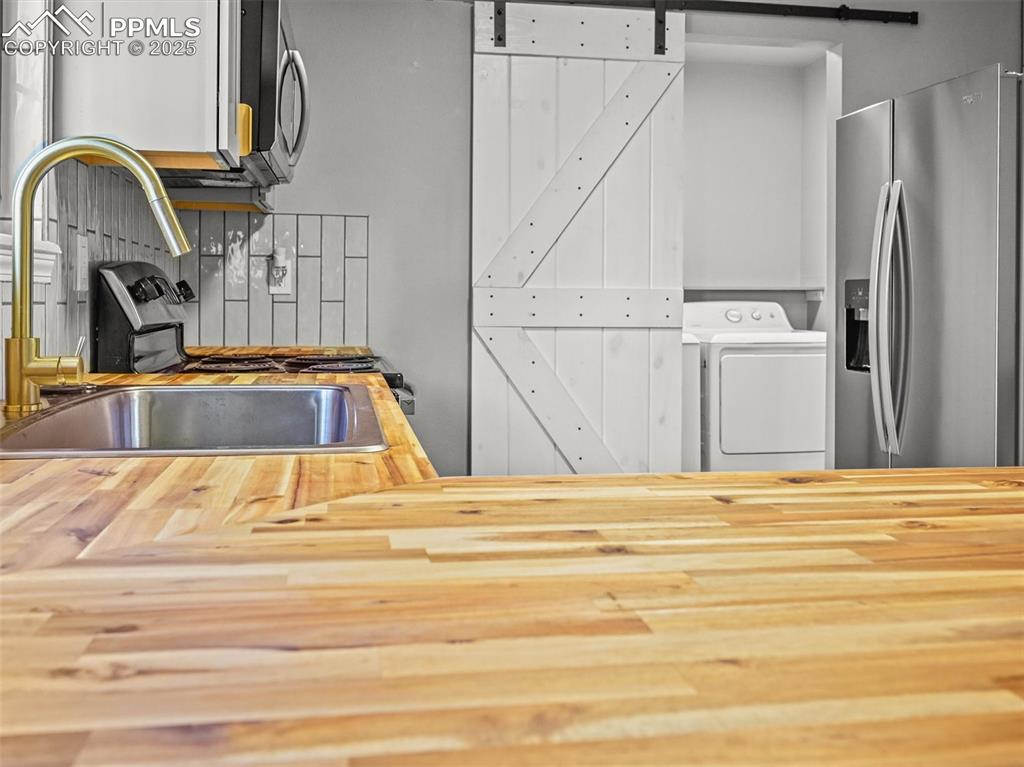 Image 16 of 47: Kitchen featuring wood counters, appliances with stainless steel finishes,
