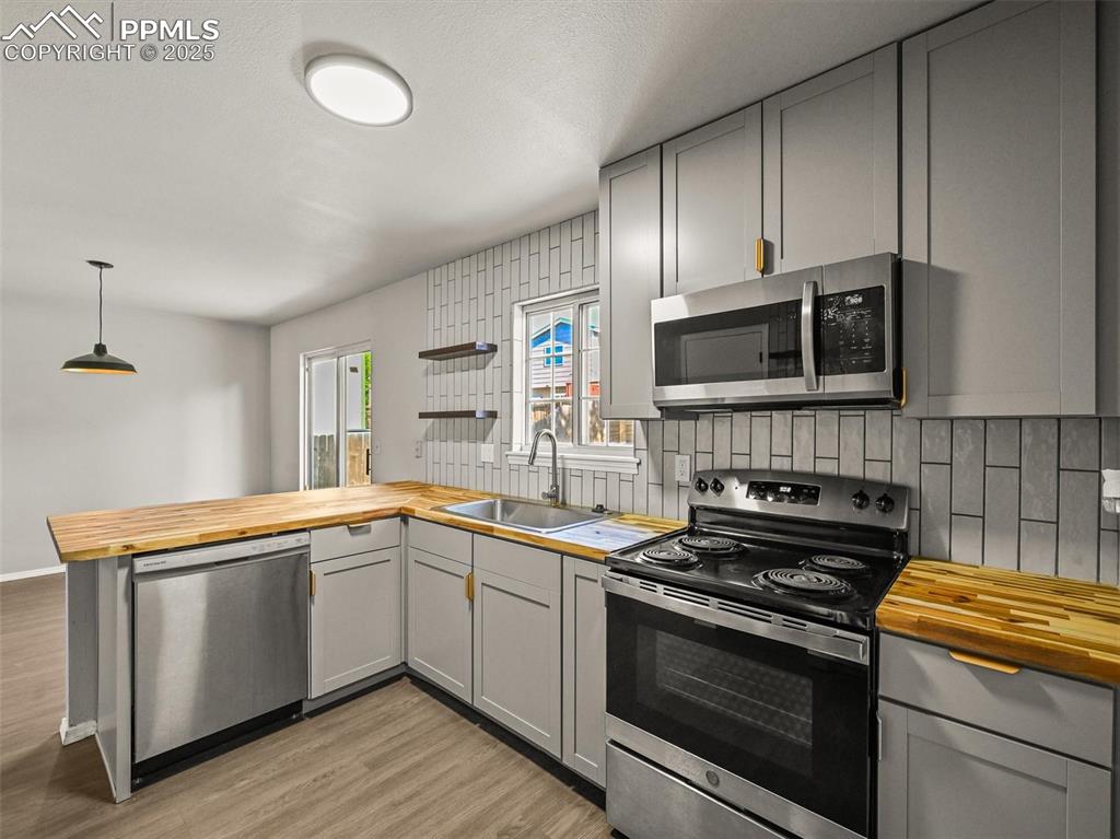 Image 19 of 47: Kitchen with butcher block countertops, stainless steel appliances, a sink,