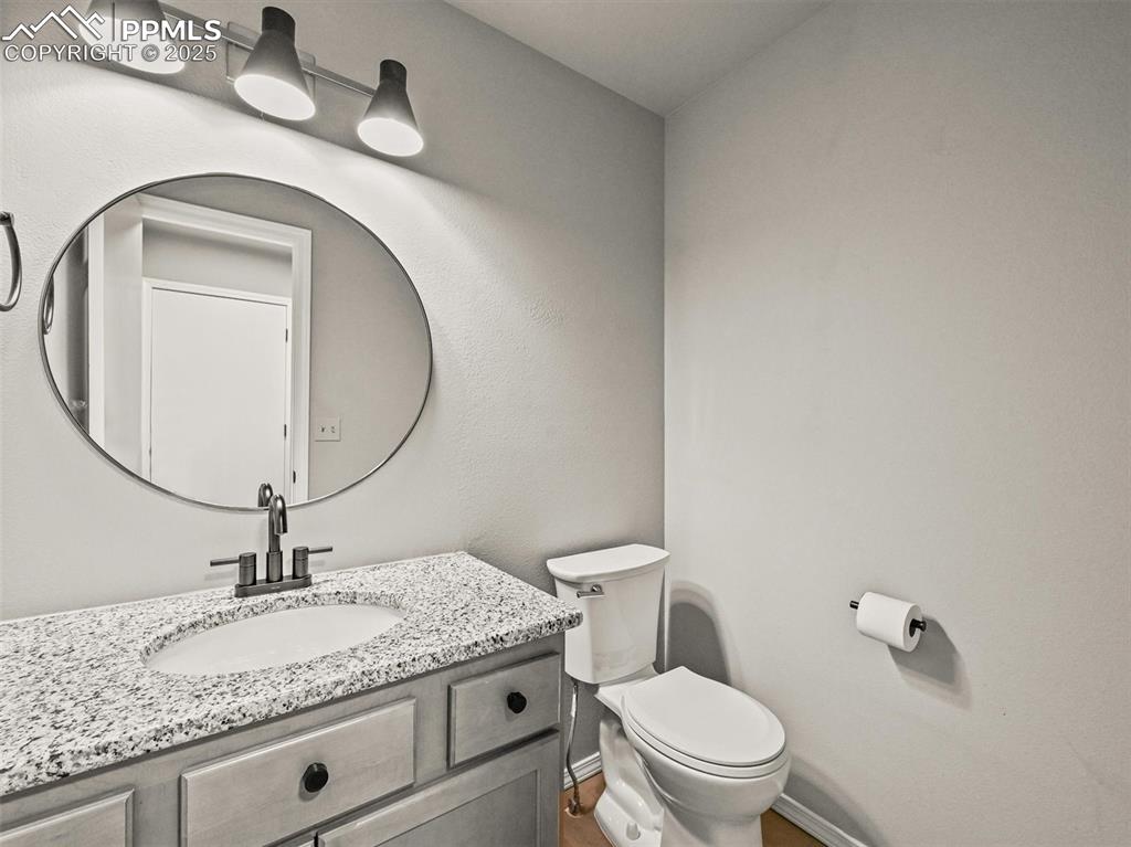 Image 21 of 47: Bathroom with toilet, vanity, baseboards, and wood finished floors