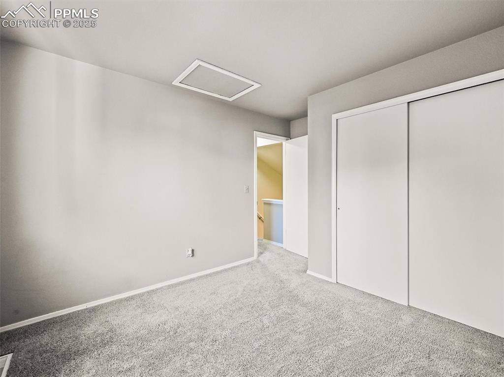 Image 33 of 47: Unfurnished bedroom with attic access, carpet floors, a closet, and baseboa