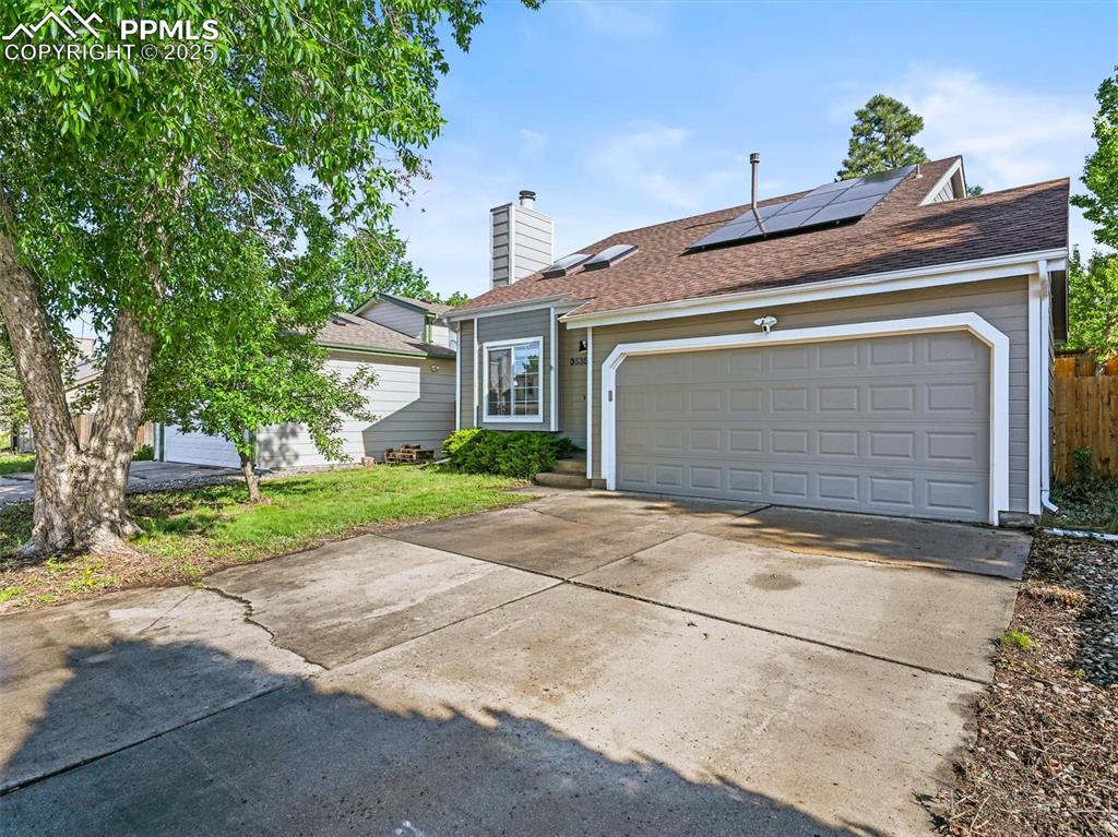 Image 5 of 47: View of front of house featuring concrete driveway, solar panels, a chimney