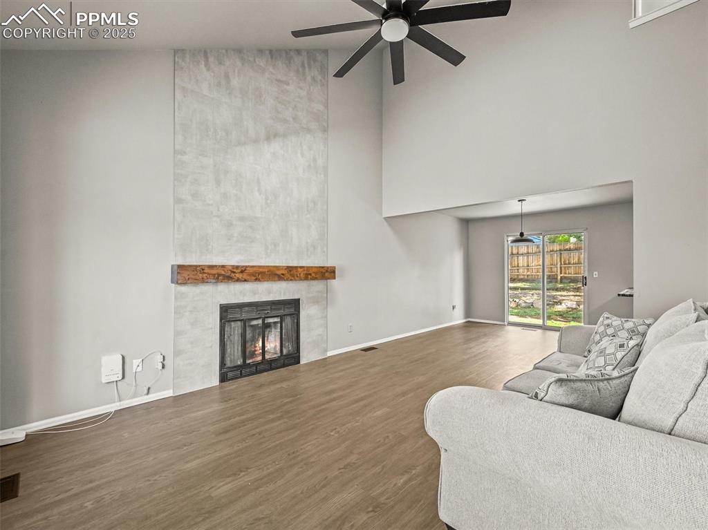 Image 6 of 47: Living room with a towering ceiling, a ceiling fan, wood finished floors, a