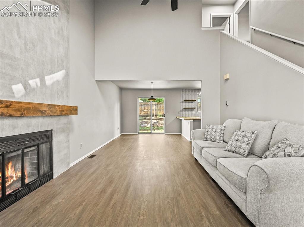 Image 7 of 47: Living area featuring a towering ceiling, ceiling fan, wood finished floors