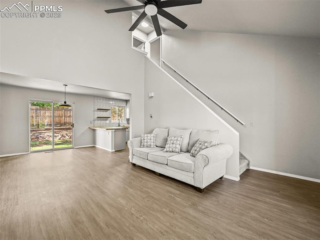 Image 9 of 47: Living area featuring stairs, a ceiling fan, wood finished floors, baseboar