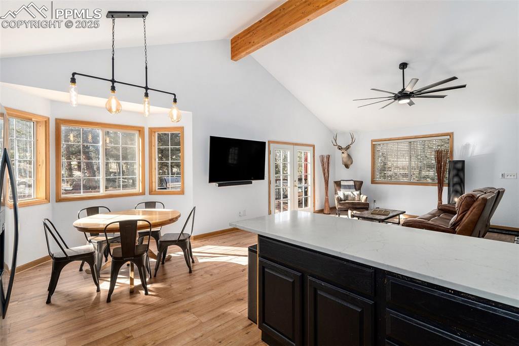 Image 11 of 25: Kitchen featuring dark cabinetry, light wood-style flooring, light stone co