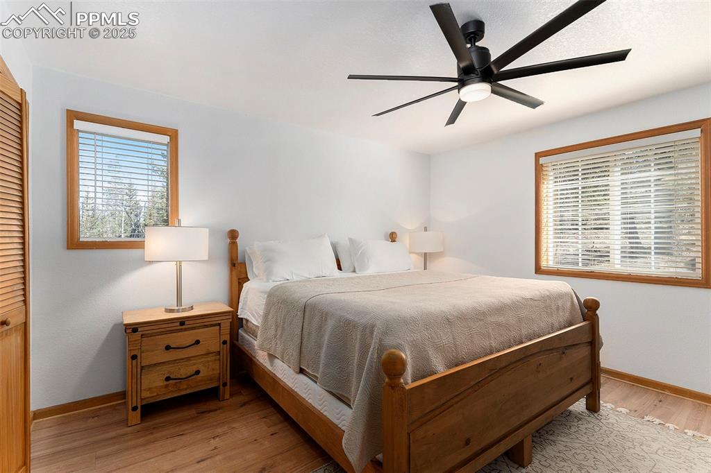 Image 13 of 25: Bedroom with ceiling fan, multiple windows, light wood-style floors, and a 